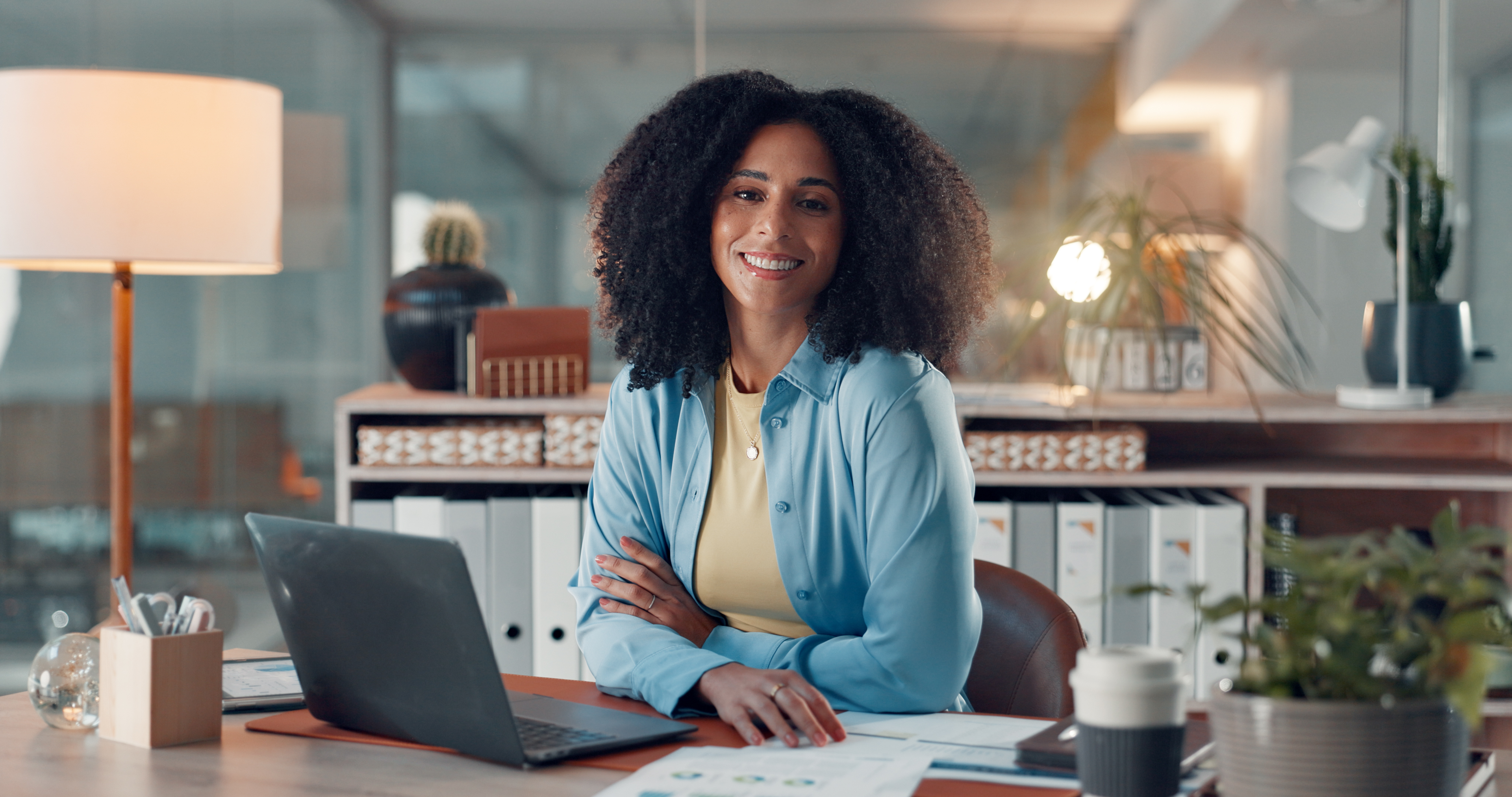 Woman, portrait and laptop with smile at startup with confidence, review or pride at digital agency. Person, computer and documents with report, graphs or stats for social media marketing